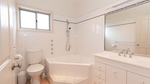 A bathroom with a toilet, bathtub, and a large mirror. - Reedy's Run - 11 Reedy's Cutting (Jindabyne)