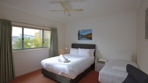 A hotel room with a bed, a bedside table, a chair, a ceiling fan, a window with curtains, and a painting on the wall. - Reedy's Run - 11 Reedy's Cutting (Jindabyne)