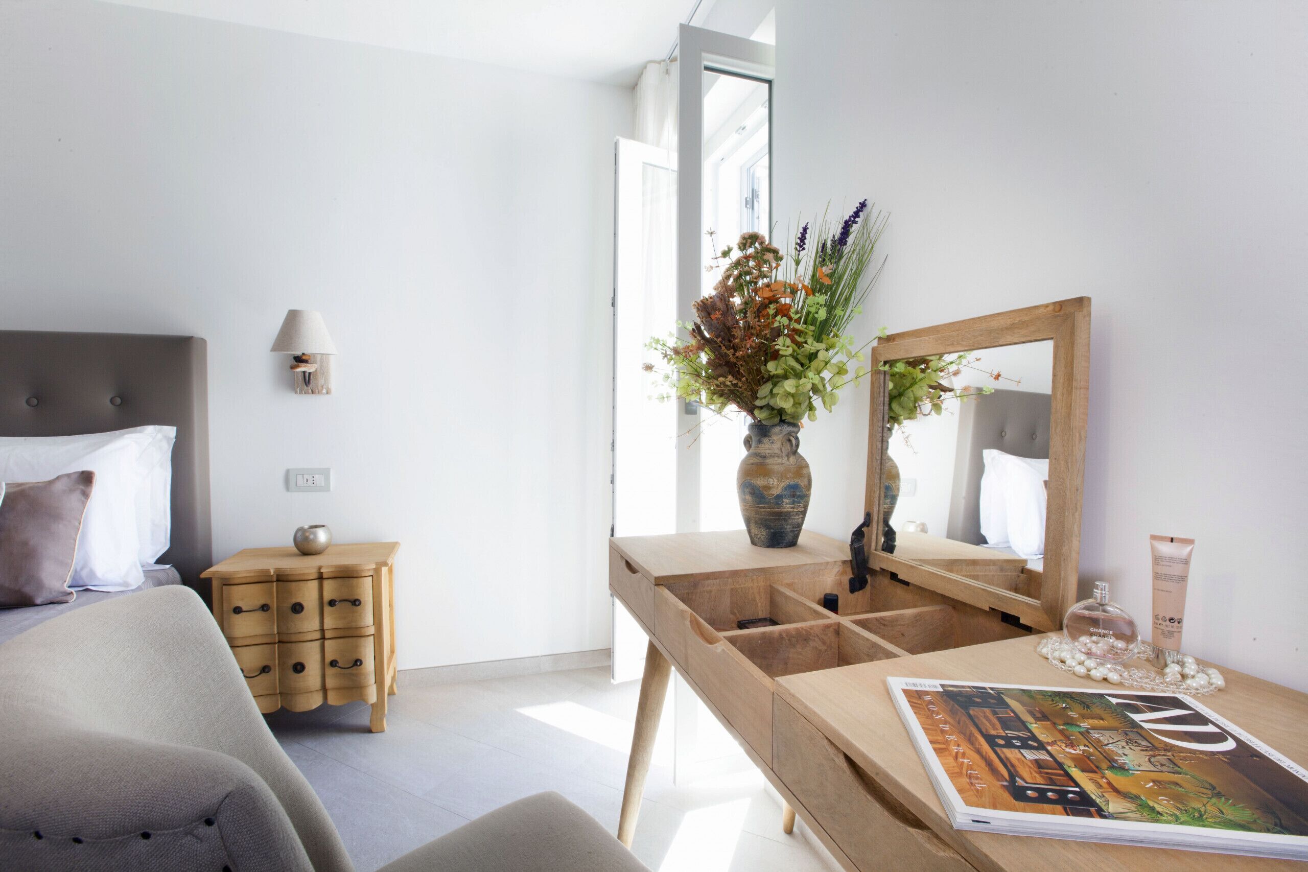 Een moderne slaapkamer met een bed, nachtkastje, kaptafel en een spiegel.