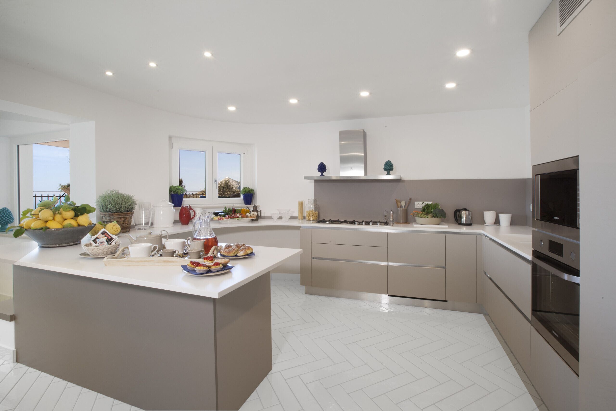 Une cuisine moderne dotée d’un îlot central, de meubles blancs et d’appareils électroménagers en acier inoxydable.