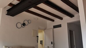 Een moderne woonkamer met een houten vloer, een bank en een plafond met zichtbare balken.
