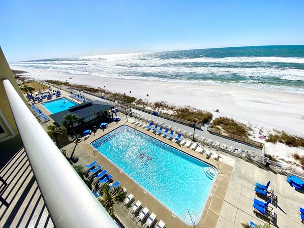 A pool area with lounge chairs and a view of the beach.