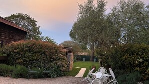 A gravel patio with outdoor furniture, a stone wall, and a pathway leading to a house.