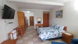 A bedroom with a bed, a desk, a chair, a TV, and a wardrobe. - Crayfish Inn no.6 (Margate)