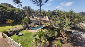 A residential area with a swimming pool, lush greenery, and a white fence. - Crayfish Inn no.6 (Margate)