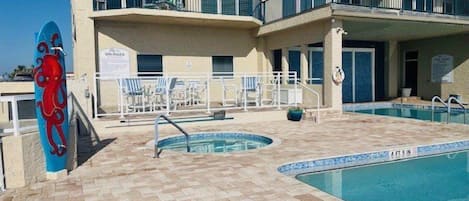 A pool area with a blue octopus decoration, lounge chairs, and a building with multiple balconies.