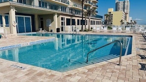 A swimming pool with a tiled deck, lounge chairs, and a building with balconies in the background. - 20th Floor Luxury in this 2 bedroom 2 bath condo - Unit 2005 Towers 10 (Daytona Beach Shores)