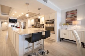 Uma cozinha moderna com ilha central, eletrodomésticos de aço inoxidável e design minimalista.