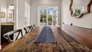 A dining area with a long wooden table, chairs, and a blue runner. - Perfect Modern Getaway with Parking Steps to Forsyth by Lucky Savannah (Savannah)
