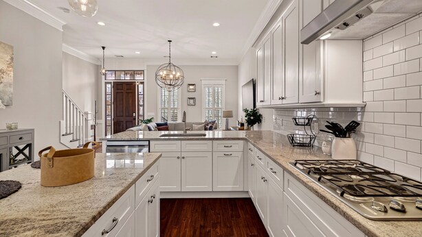 A modern kitchen with white cabinetry, a granite countertop, and a stainless steel stove. - Perfect Modern Getaway with Parking Steps to Forsyth by Lucky Savannah (Savannah)