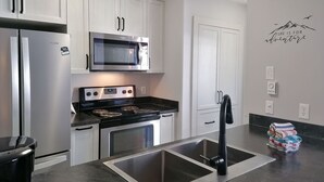 Een moderne keuken met roestvrijstalen apparatuur, witte kasten en een zwart aanrecht.