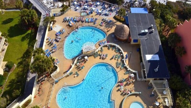 An aerial view of a resort with multiple swimming pools, sun loungers, and a large building. - Steps from the beach! Pool, Pickleball, and Tennis Courts! (Miramar Beach)