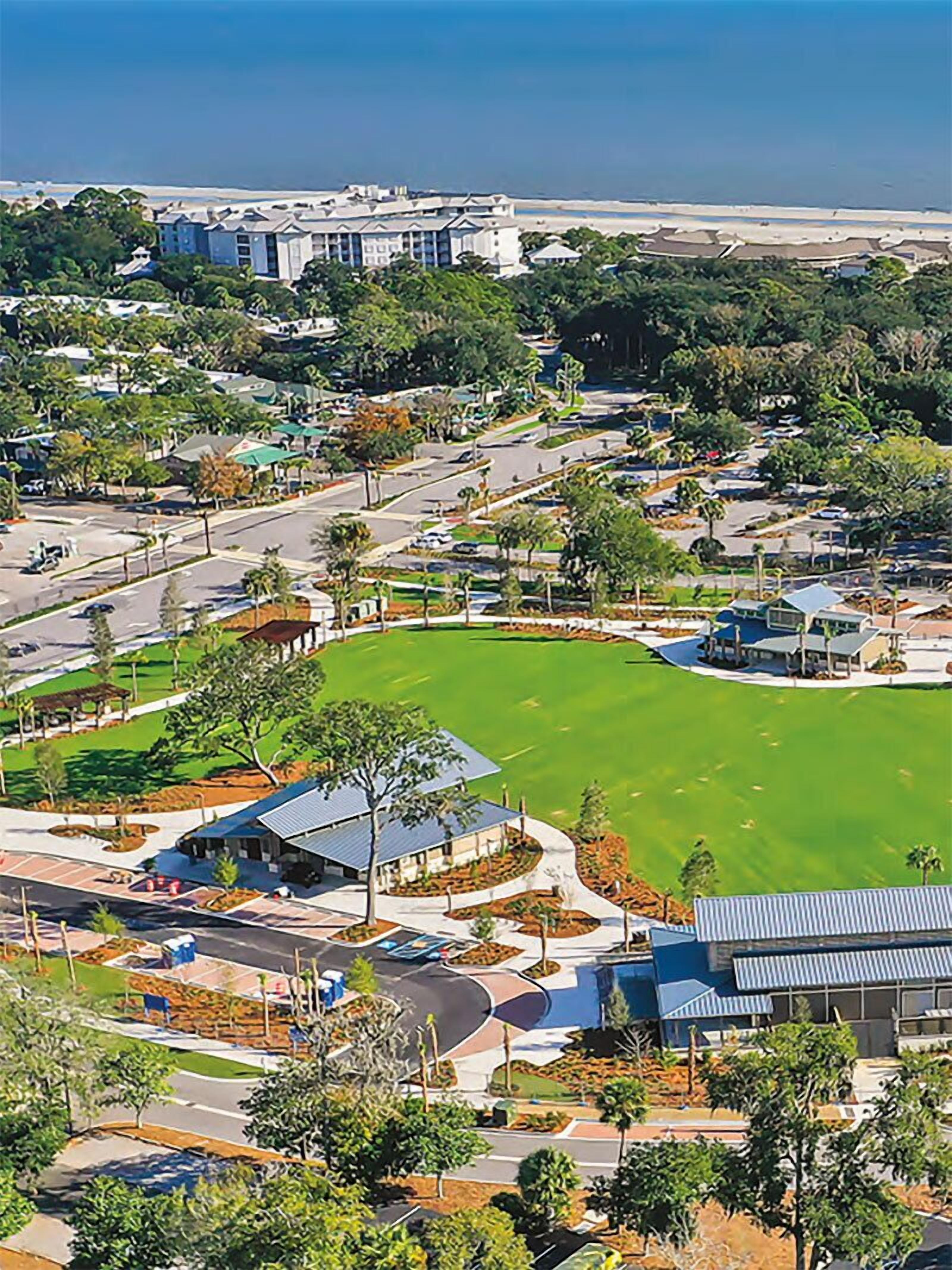 A resort with a large green lawn, a parking area, and a view of the ocean.