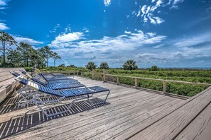 Relax on the deck with comfortable lounge chairs overlooking a serene landscape.