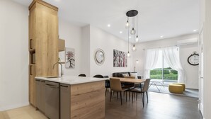 Une cuisine moderne dotée d’un îlot central en bois, d’appareils électroménagers en acier inoxydable et d’un coin repas avec une table et des chaises.