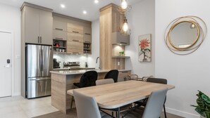 Une cuisine moderne dotée d’un réfrigérateur en acier inoxydable, de meubles en bois et d’un coin repas avec une table et des chaises en bois.