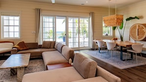 A spacious living room with a large sectional sofa, a dining table with chairs, and a ceiling fan.