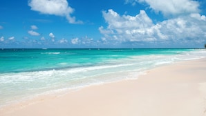 A beach with clear turquoise waters and white sand.