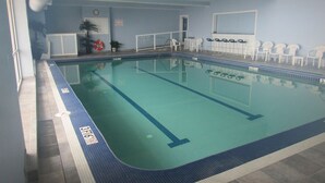 En inomhuspool med banmarkeringar, en klocka och en livräddarstol.