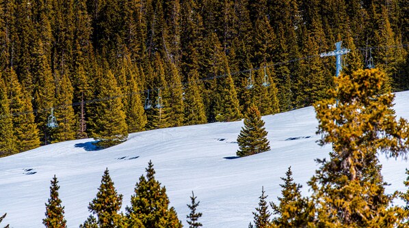 A snowy ski slope with a ski lift and dense forest in the background. - Spectacular views, just steps from Super Bee, Vaulted Ceilings! Free WiFi (copper mountain)