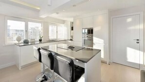 A modern kitchen with a central island, stainless steel appliances, and a view of the city.
