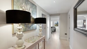 A hallway with a console table, two lamps, and a large abstract painting.