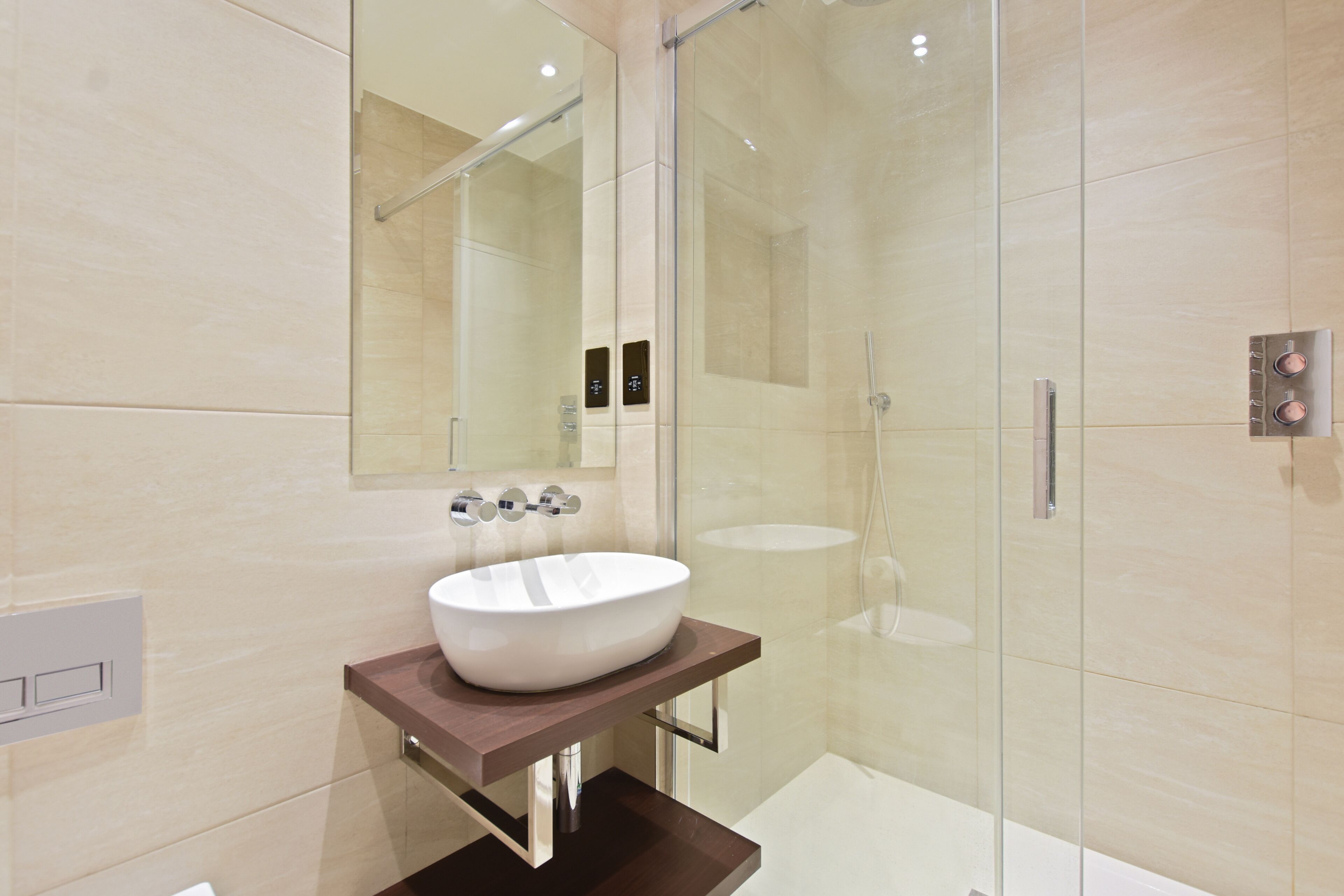 A modern bathroom with a large mirror, a vessel sink, and a glass-enclosed shower.