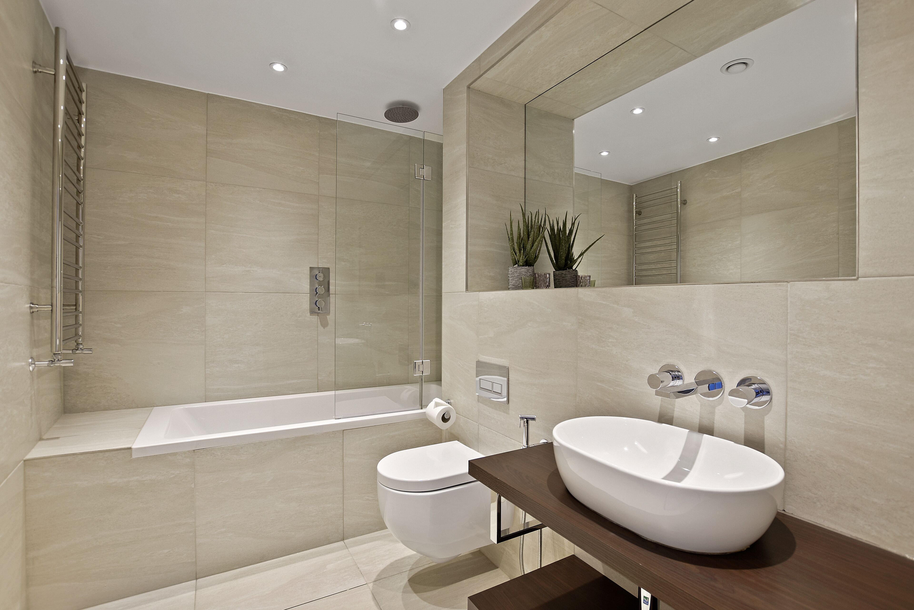 Ein modernes Badezimmer mit einer Glaskabine zur Dusche, einer weißen Toilette und einem großzügigen Waschtisch.