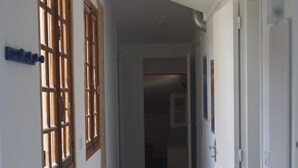 A narrow hallway with wooden flooring, white walls, and two windows with wooden frames. - T3 2nd floor of the villa of the sea (Hyères)