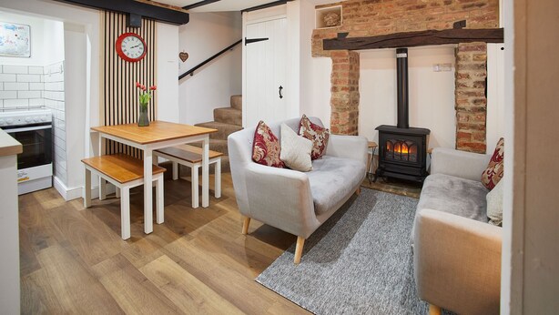 A cozy living room with a sofa, a wooden table, and a fireplace.