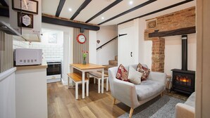 A cozy living room with a fireplace, a dining area, and a kitchen with white appliances.