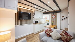 A modern kitchen with white cabinets, a built-in microwave, and a wooden accent wall.