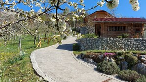 Ein Garten mit Steinsäulen und einem gewundenen Weg, der zu einer Holzhütte mit rotem Dach führt.