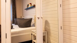 A room with a bed, a chair, and a shelf with books. - House (Simonsberg)