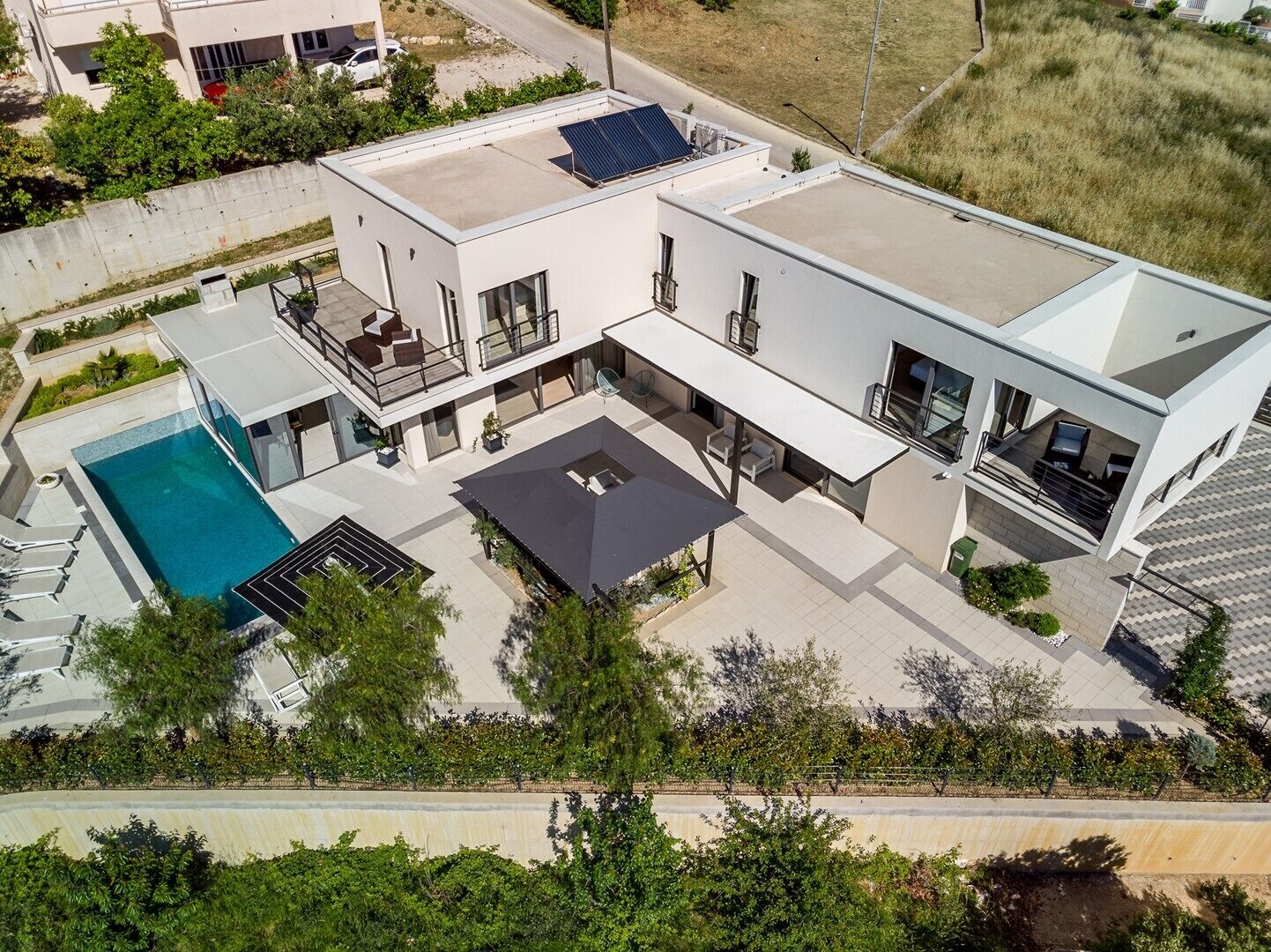 A modern two-story house with a swimming pool, solar panels, and a covered patio area.