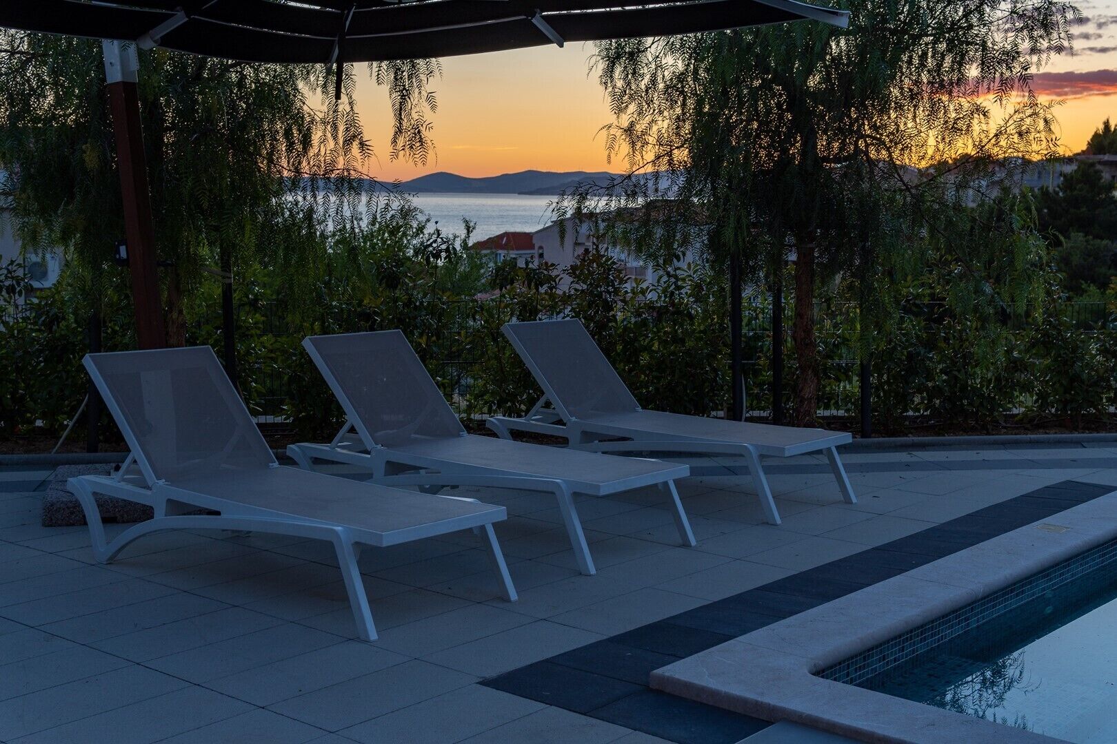 Un espace aménagé au bord de la piscine, comprenant trois chaises longues et une piscine.