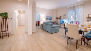Ein modernes Wohnzimmer mit einem blauen Sofa, einem Glastisch und einem Essbereich mit einem weißen Stuhl und Tisch.