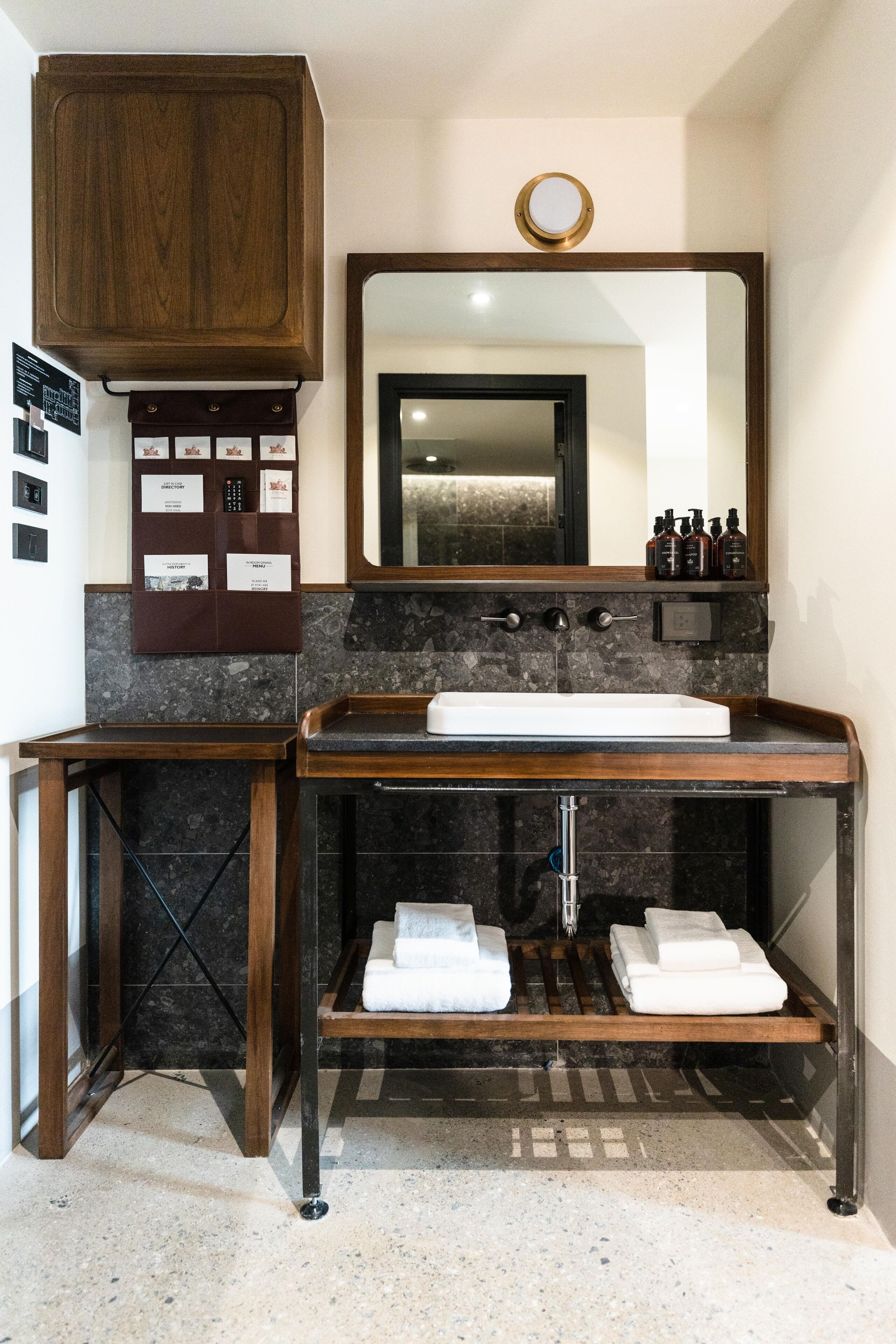 Un baño con tocador de madera, un espejo grande y un perchero para toallas.