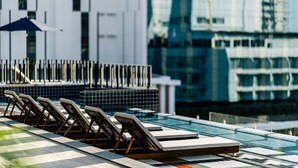A modern hotel pool area with lounge chairs and a glass barrier. - Payaa Hotel (Pattaya)