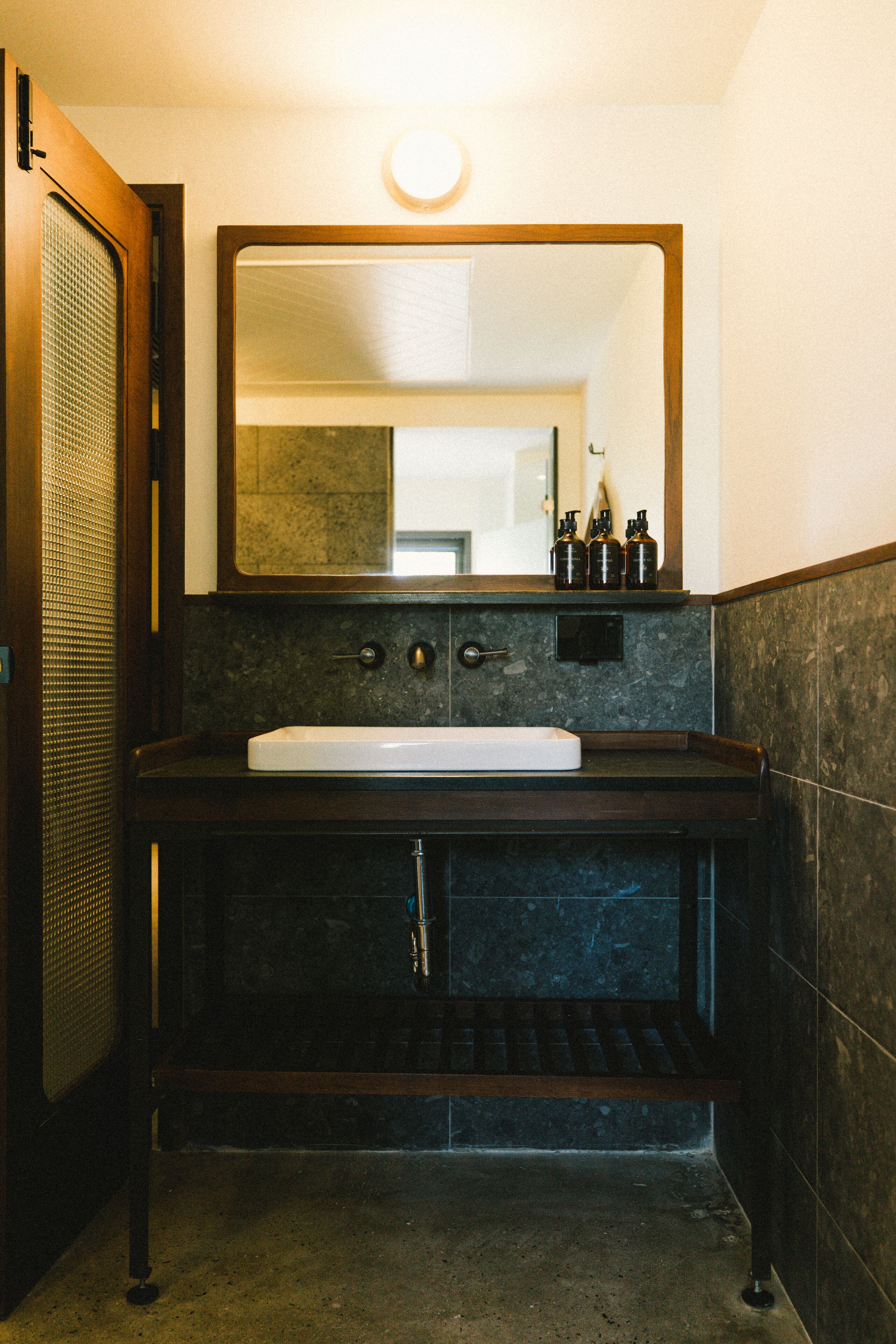 A bathroom with a dark marble sink, a mirror above it, and a towel rack below.