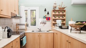 A kitchen with wooden cabinets, a sink, a stove, and various kitchen utensils. - Feels Like Your Home at Ermioni (Ermionida)