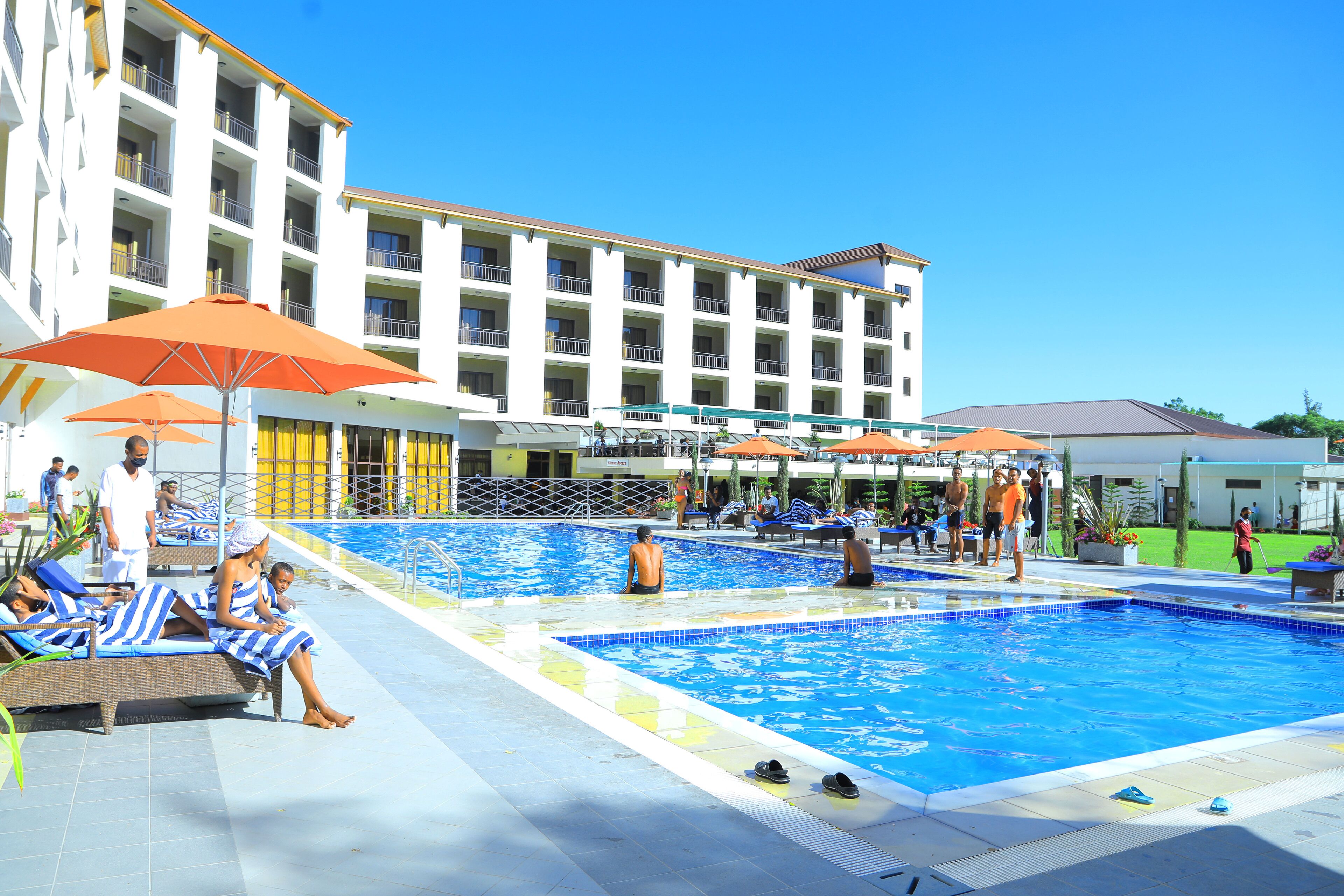 A hotel pool area with lounge chairs, umbrellas, and a building with multiple balconies.