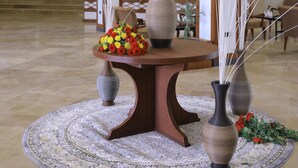 A lobby with a round table, three vases with white sticks, and a patterned rug. - Haile Resort Adama (Adama)