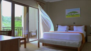 A bedroom with a bed, a chair, a table, and a view of greenery through the window. - Haile Resort Adama (Adama)