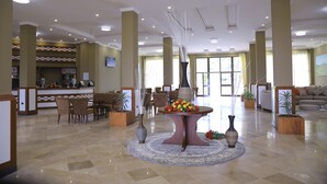 A spacious lobby with a reception desk, seating area, and a decorative table with flowers. - Haile Resort Adama (Adama)
