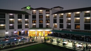Un hotel con varios pisos, piscina y zonas de estar al aire libre.