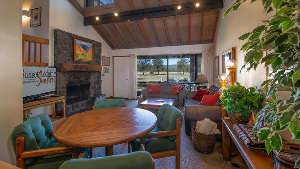 Un salón acogedor con chimenea de piedra, techo de madera y un ventanal con vistas al exterior.