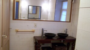 Une salle de bain avec un meuble-lavabo en bois, deux bols noirs, un miroir et un porte-serviettes.