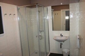 A bathroom with a glass-enclosed shower, a sink, and a toilet.