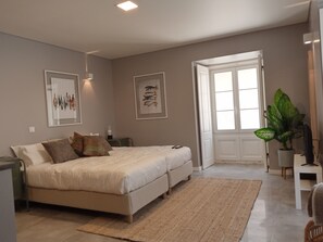 A bedroom with a bed, bedside tables, a window, and a potted plant. - Casa das Quatro Cabeças (Setubal)